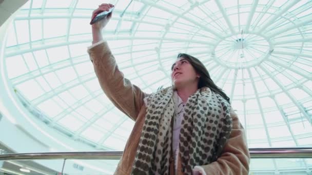 Seorang narablog perempuan di sebuah pusat perbelanjaan mengambil gambar, mengambil foto selfie, siaran langsung, berkomunikasi dengan para pengikut — Stok Video