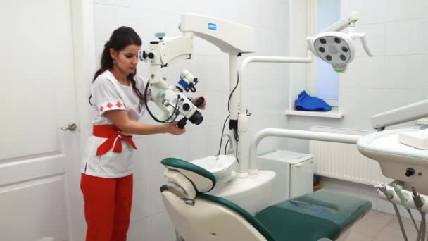 白俄罗斯明斯克- - 2019年11月21日，年轻的女牙医准备好工作柜，把显微镜放在工作位置上 — 图库视频影像