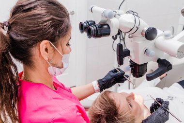 Bir kadın profesyonel diş hekimi ofisinde bir stamotolojik mikroskop ile bir kadın hasta inceler. Stamotoloji mesleği kavramı