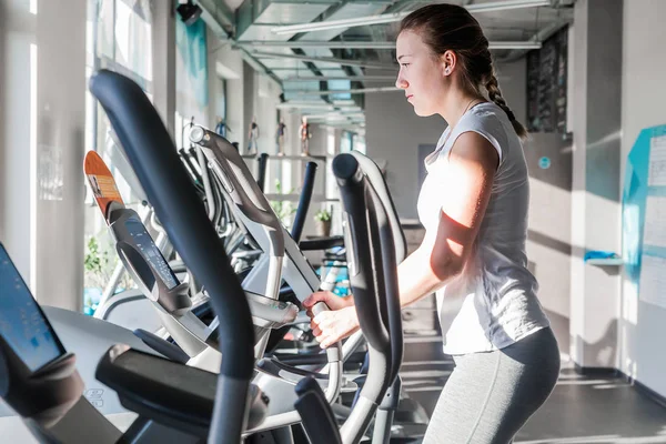 Spor salonunda egzersiz yapan bir kız kardiyo simülatöründe.