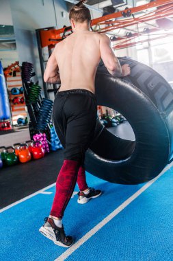 Spor salonunda lastiği patlayan tişörtsüz bir adam. Dikey fotoğraf