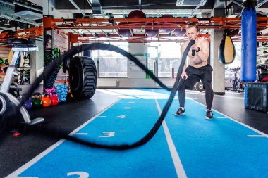 İşlevsel antrenman fitness salonunda iple güçlü adam eğitimi.