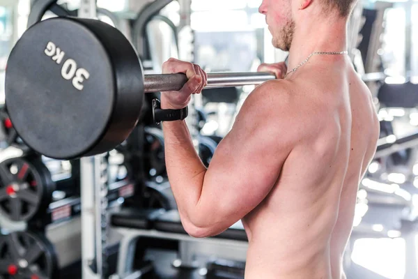 Sport, musculation, style de vie et concept de personnes - jeune homme avec haltère flexion des muscles dans la salle de gym — Photo
