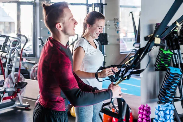 Un hombre y una mujer joven tienen en sus manos bucles trx, se están preparando para hacer ejercicios — Foto de Stock