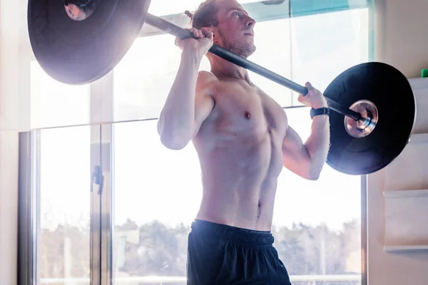 sport, bodybuilding, lifestyle and people concept - young man with barbell flexing muscles in gym