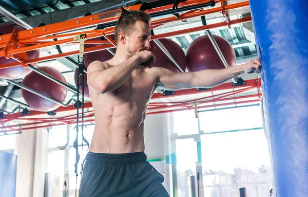 Hemdloser muskulöser Sportler schlägt beim Boxtraining im Kampfclub auf Boxsack ein — Stockfoto