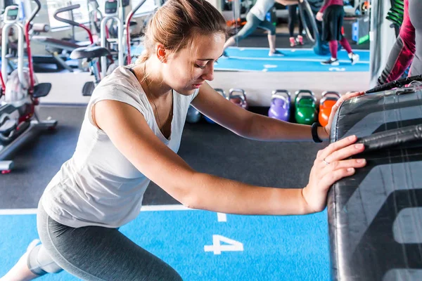 Ajuste atleta femenina haciendo ejercicio con un neumático enorme, girando y volteando en el gimnasio . — Foto de Stock