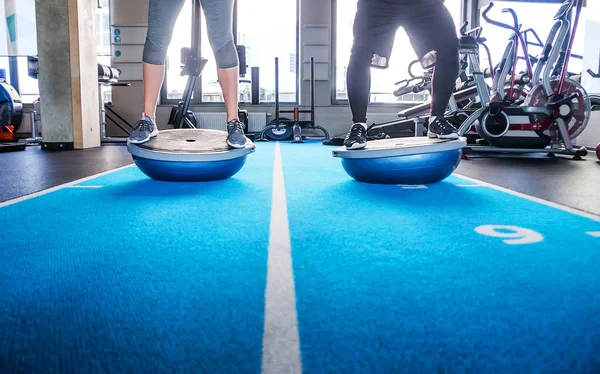 Patas masculinas y femeninas en bola bosu en gimnasio — Foto de Stock