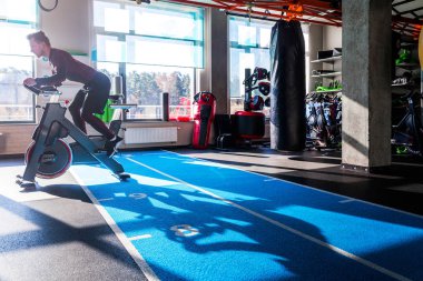 Sporcu güneşli bir havada bir spor salonunda kardiyovasküler ekipmanla meşgul..