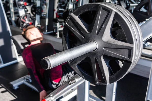 Attraktiver junger Mann beim Beinpressen an einem Gerät im Fitnessstudio an einem Tag. — Stockfoto