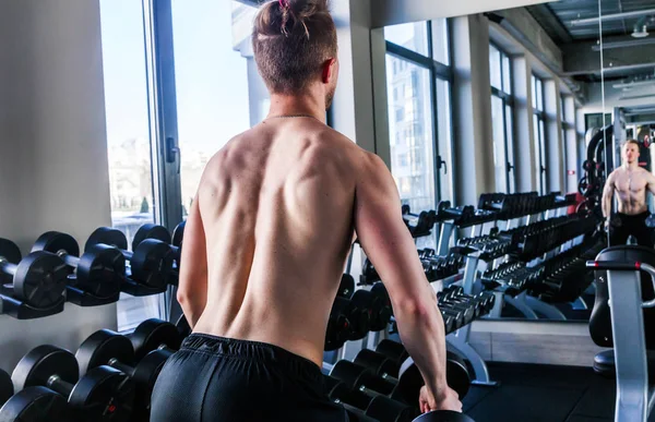 Sportlicher Mann mit nacktem Oberkörper im Fitnessstudio hebt Hanteln. — Stockfoto