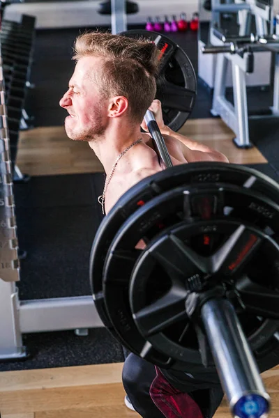 Strong muscular man with muscles performing weightlifting training sport with heavy metal barbell weight and hard face expression — 스톡 사진