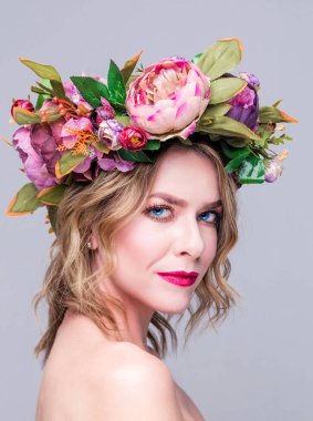 Gri arka planda parlak çiçekleri olan güzel bir kadın model.