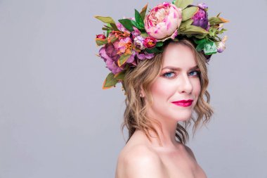 Gri arka planda parlak çiçekleri olan güzel bir kadın model.