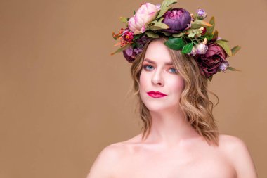 Kafasında parlak çiçekler olan güzel, genç bir manken.