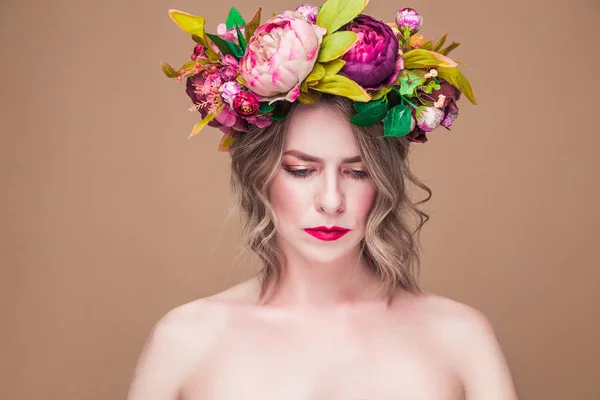 Красивая молодая женщина модель с яркими цветами на голове на охристый цвет фона — стоковое фото