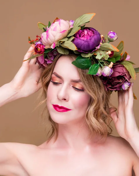 Hermosa joven modelo con flores brillantes en la cabeza en el fondo de color ocre —  Fotos de Stock