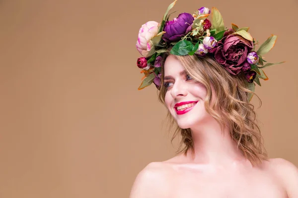 Šťastná krásná mladá žena model s jasnými květy na hlavě úsměv na okrové barvy pozadí — Stock fotografie
