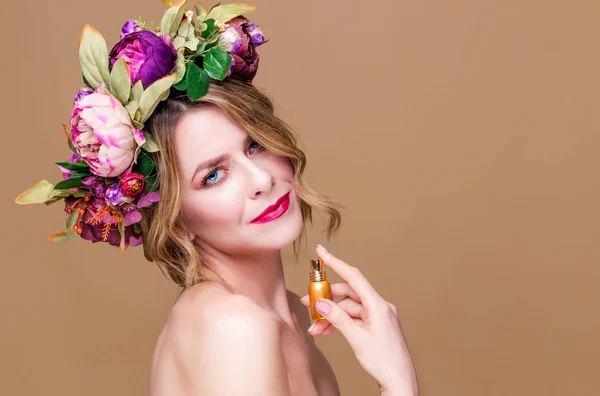 Retrato de cerca de la mujer joven en la corona floral rociar perfume aislado sobre fondo ocre —  Fotos de Stock