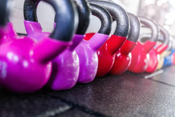 Sinos de kettlebell coloridos em um ginásio. Vermelho e violeta — Fotografia de Stock
