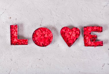 Beton zemin üzerinde kırmızı kalplerden yapılmış bir yazı aşkı.