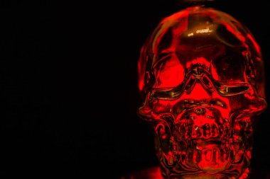 Siyah arka planda kırmızı ışıkla taçlandırılmış cam kafatası
