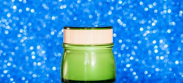 Frasco verde com creme facial em um fundo azul — Fotografia de Stock