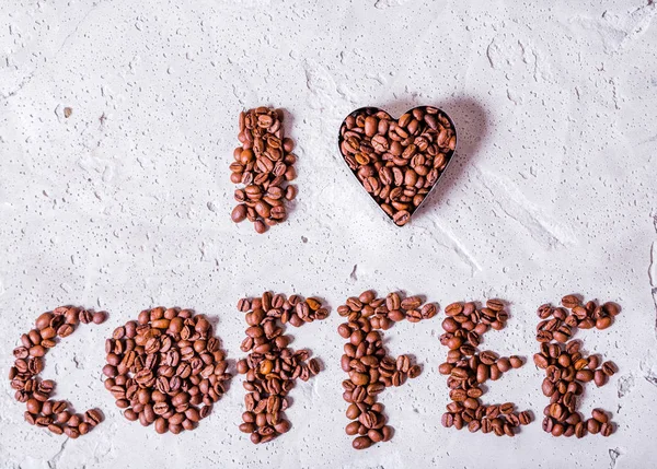 Napis Kocham kawę jest wykonana z ziaren kawy na konkretnym tle. — Zdjęcie stockowe