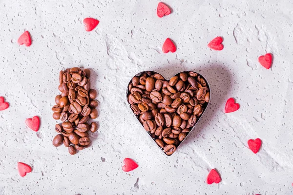Letter and heart made of coffee beans on a concrete background.
