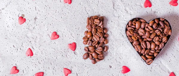 Letter and heart made of coffee beans on a concrete background.