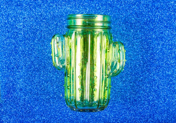 Vidro verde vidro na forma de um cacto sobre um fundo azul — Fotografia de Stock