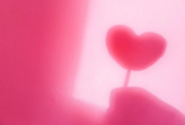 Concept modern abstract background of shadow heart in hand on a pink wall. — 스톡 사진