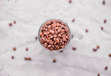 Beyaz fincanda kavrulmuş kahve çekirdekleri. Hafif beton arka plan. Üst görünüm