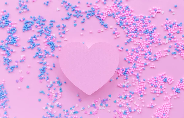 Papírové růžové srdce na pozadí dekorativních kuliček v modré a růžové — Stock fotografie