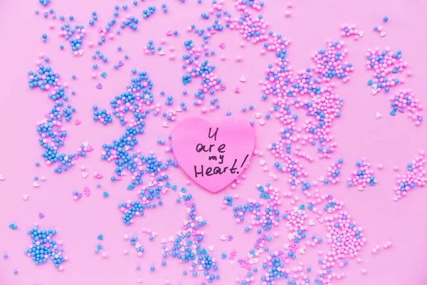 在蓝色和粉色装饰球的背景上的纸粉色心脏。 有一个关于心脏的文字 — 图库照片