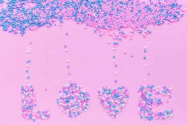 Wolke aus dekorativen Kugeln auf rosa Hintergrund mit herabfallenden rosa, lila und blauen Herzen und Schriftzug Liebe — Stockfoto