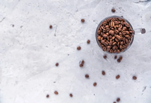 Roasted coffee beans in white cup.  Light concrete background. Top view
