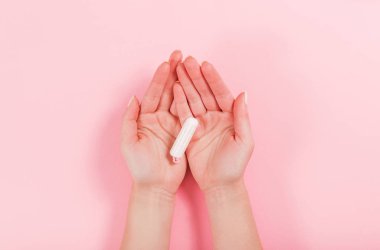 Kadın eli pembe arka planda tampon tutar.
