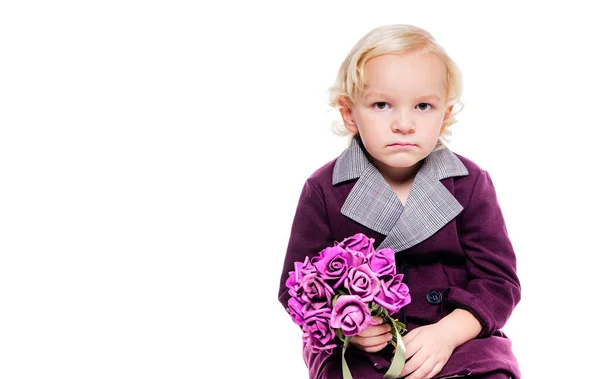 Petit garçon à la mode dans un élégant costume bordeaux et avec un bouquet de fleurs à la main sur un fond blanc. Le garçon est triste, contrarié, en colère — Photo