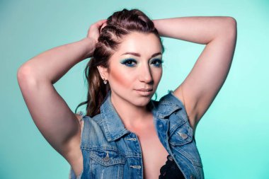 Beautiful brunette girl with blue makeup, pigtails and loose curly hair on a mint color background