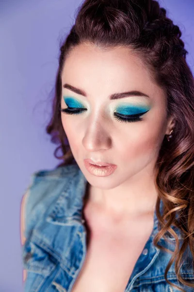 Schöne brünette Mädchen mit blauem Make-up, Zöpfen und lockigem Haar auf lila Hintergrund — Stockfoto