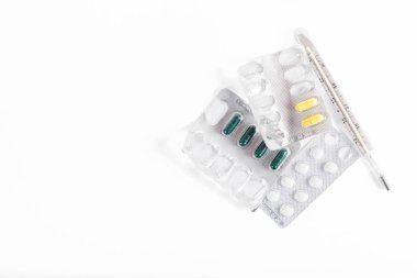 Beyaz arka planda termometre ve boş hap kutusu