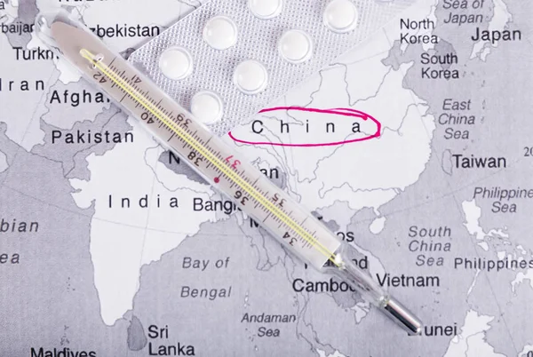 China on the world map. The thermometer lies on the territory of China as a symbol of the outbreak of a new type of coronavirus