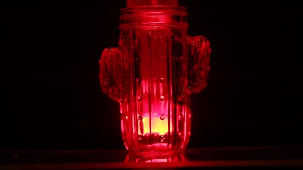 杯子靠着红灯站着 液体在红灯中流动 — 图库视频影像