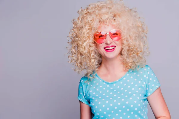 Beautiful retro-style blonde girl with voluminous curly hairstyle, in a blue polka-dot blouse and pink glasses on a gray background — Stock Photo, Image