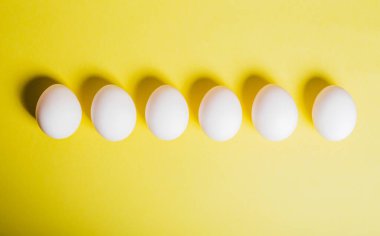Yumurtalar sarı arka plandaki alt kenar boyunca sıralanmış, kopyalama alanı. Mutlu Paskalya Günleri. Düz yatıyordu. Yatay.