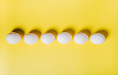 Yumurtalar sarı arka plandaki alt kenar boyunca sıralanmış, kopyalama alanı. Mutlu Paskalya Günleri. Düz yatıyordu. Yatay.