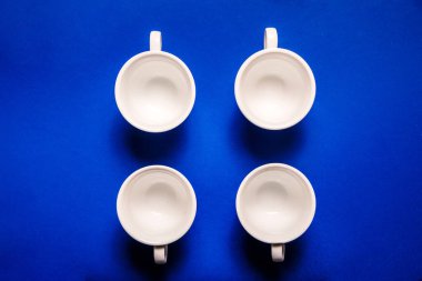 Mavi arka planda dört boş beyaz kahve fincanı. Üst görünüm