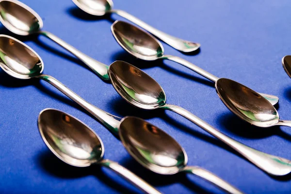 Many teaspoons or coffee spoons on a blue background. Top view