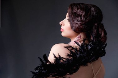 Devekuşu tüylü güzel esmer kadın kameranın önünde oturuyor ve poz veriyor. Yatay fotoğraf